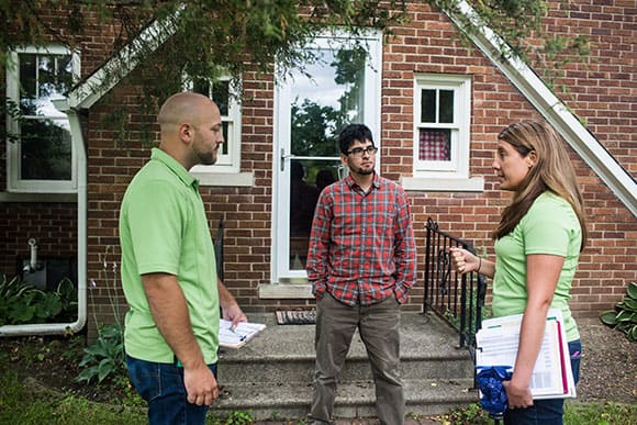 Contractors speak with a homeowner