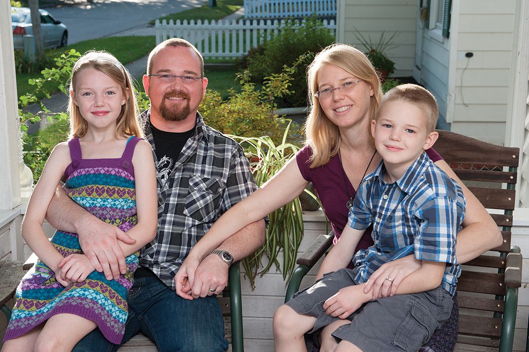 Family of four sitting on the porch of their home