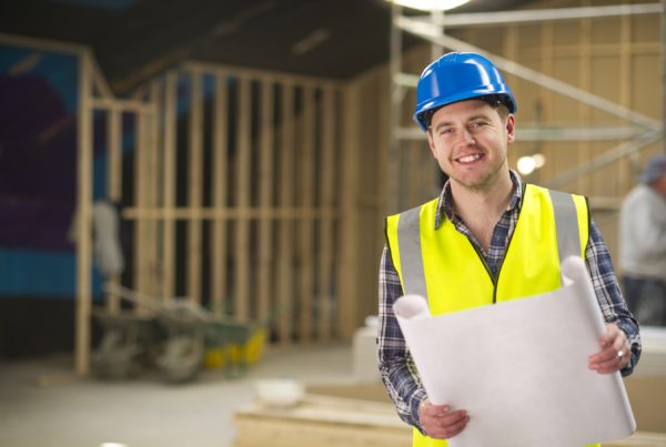 Contractor smiling and holding blueprints