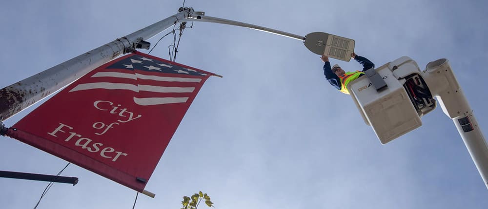 Utility worker in a bucket truck adjusting a street light with LED lights