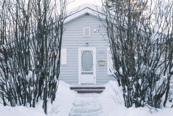 small house in the winter time covered in snow with a shoveled side walk