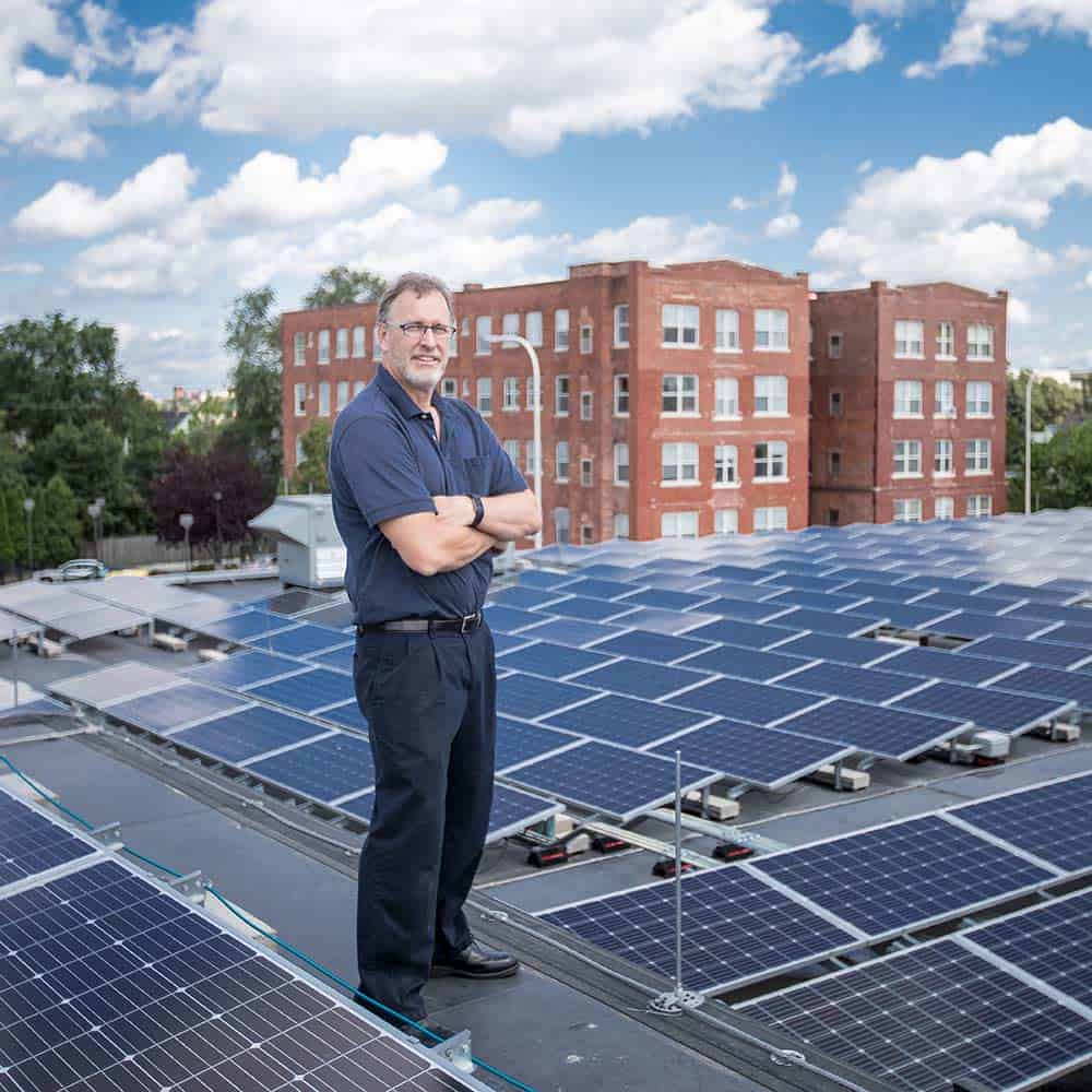 Walt Dindoffer standing on the roof of a building with solar panels covering the roof