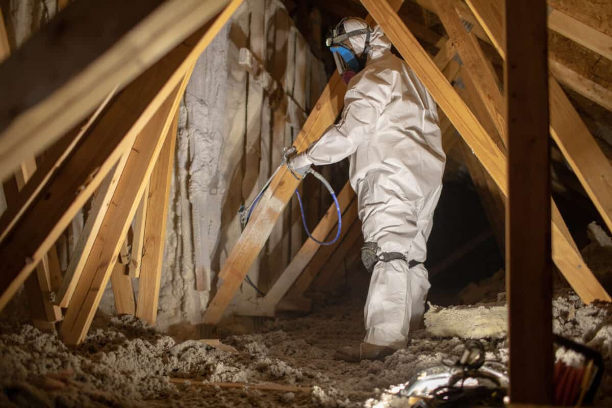 Contractor spraying insulation in an attic