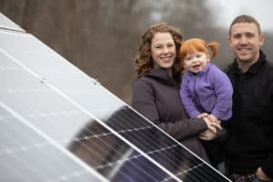 The Drury family standing next to solar panels