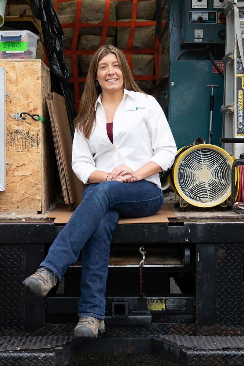 Contractor sitting on the bumper of her truck and posing for the camera