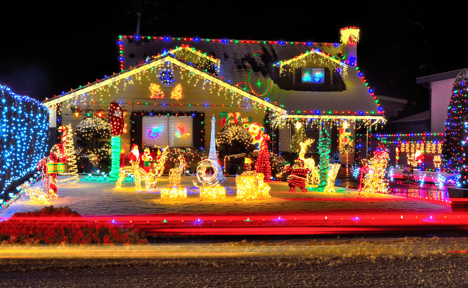 House decorated with colorful string lights and light-up holiday figures in the front yard