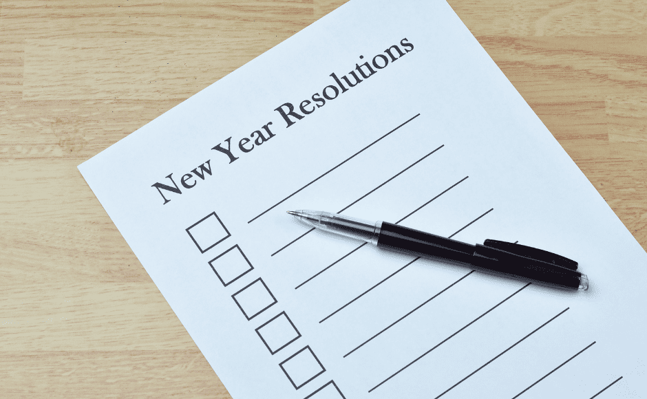 A black ink pen on top of a paper with "New Year Resolutions" typed across the top with a series of check boxes and blank lines down the paper