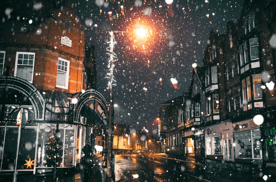 Snowy small town street at night lit up by streetlights