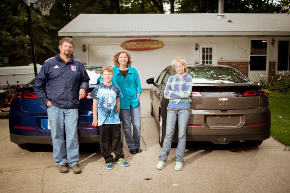 Family standing in front of their electric vehicles